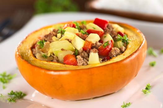 Stuffed baked pumpkin filled with zucchini, red bell pepper, minced meat, onions and garnished with parsley (Selective Focus, Focus one third into the stuffing)