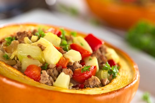 Stuffed baked pumpkin filled with zucchini, red bell pepper, minced meat, onions and garnished with parsley (Selective Focus, Focus one third into the stuffing)