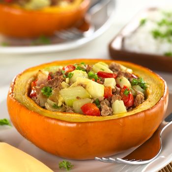 Stuffed baked pumpkin filled with zucchini, red bell pepper, minced meat, onions and garnished with parsley (Selective Focus, Focus one third into the stuffing)