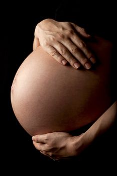 close up of a pregnant womans stomach, isolated on black background.