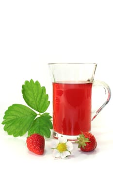 a glass of strawberry tea with fresh strawberries, strawberry leaf and flower