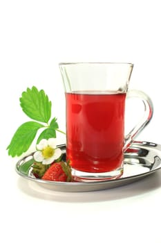 a glass of strawberry tea with fresh strawberries, strawberry leaf and flower