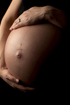close up of a pregnant womans stomach, isolated on black background.