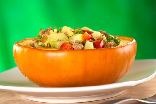 Stuffed baked pumpkin filled with zucchini, red bell pepper, minced meat, onions and garnished with parsley (Selective Focus, Focus one third into the stuffing)