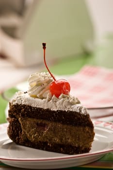 Slice of chocolate cake with cherry on the plate