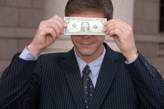Man holding one dollar bill in front of his eyes