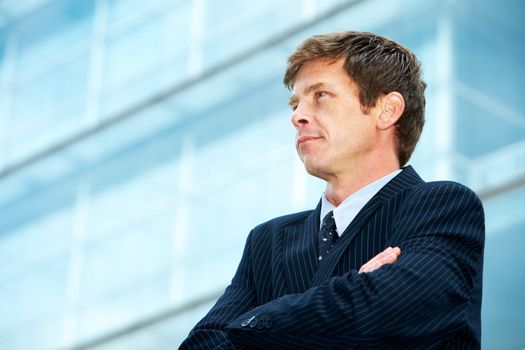 Man outside office building with arms crossed