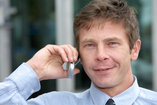 Man using cell phone outdoors, smiling, close-up