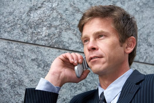 Man on cell phone by building wall, low angle close-up