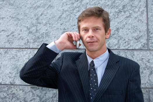 Man on cell phone by building wall, frontal portrait