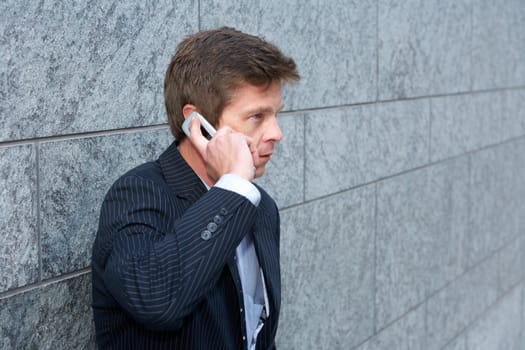 Man by building wall using cell phone