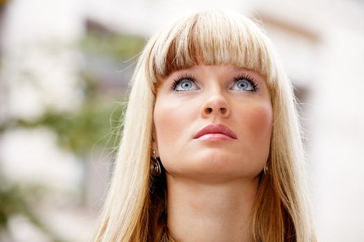 Portrait of young woman looking up outdoors in city