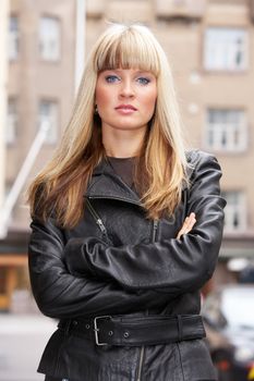 Portrait of young woman standing in city, looking at camera