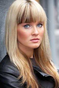 Young woman leaning to wall, looking at camera, close-up