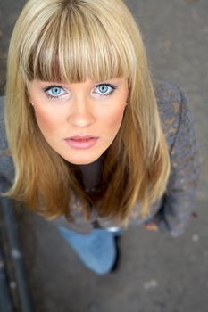 Young woman standing on sidewalk, looking at camera, elevated view