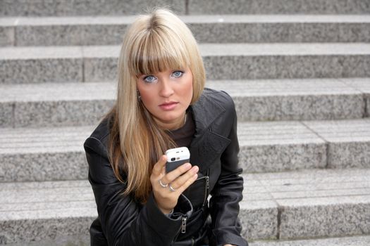 Young woman holding mobile phone, looking at camera