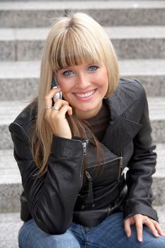 Young woman using mobile phone, looking at camera, smiling