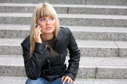 Young woman on mobile phone, looking away, sitting on stairway