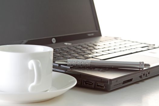 A cup of coffee and a pen on a laptop 