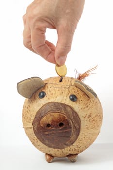 Saving, male hand putting a coin into piggy bank. 