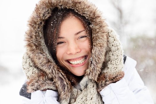 winter woman happy outside in snow smiling joyful on snowing winter day. Cute closeup portrait of beautiful mixed race Caucasian Asian girl cheerful and excited outdoors.