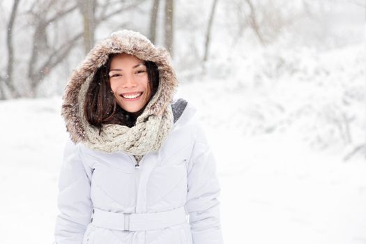 Snow winter woman portrait outdoors on snowy white winter day. Beautiful asian girl smiling happy outside.