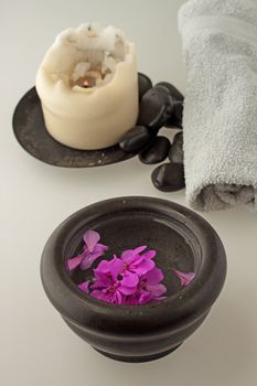Geranium in a black stone cup, with candle, stones and towel