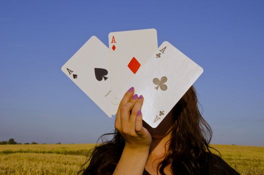 Young woman,holding cards in front of her face. Three of a kind.