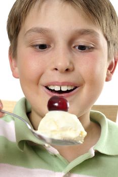 A smiling wide eyed boy holding a large scoop of ice cream in his spoon.