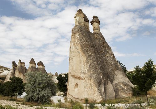 landscape of groups of limestone wind weathered to what are known as fairy chimneys. horizontal with crop area and copy space, cloudy blue sku and wilderness environment