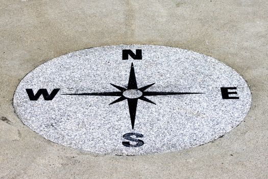 Compass found on a sidewalk on a granit background