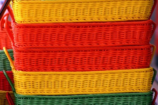 Stack of orange yellow and green baskets at a market place