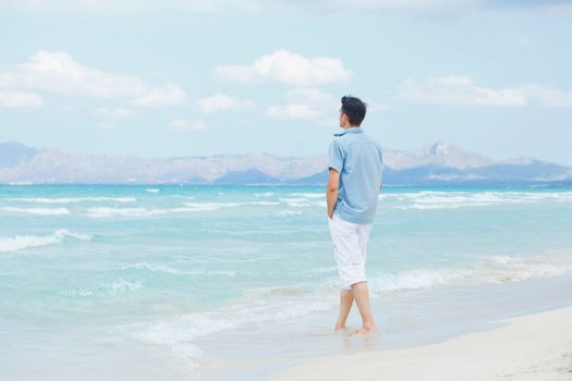 Handsome young man walking near blue sea.