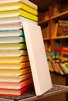 Book with white cover staying at stack of colorful books