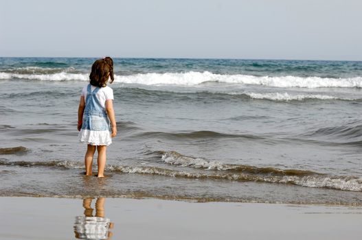 Child is standing in the ocean alone.