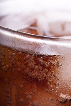 Cold cola in a glass with ice cubes. Macro view.