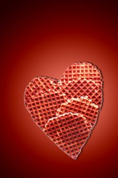 Fresh crisp waffles, In the form of heart, isolated on dark red background