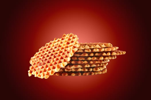 Fresh crisp waffles isolated on dark red background