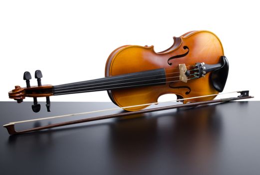 Violin on top of dark table partially isolated on white background.