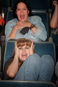 Screaming women watch scary movie in theater