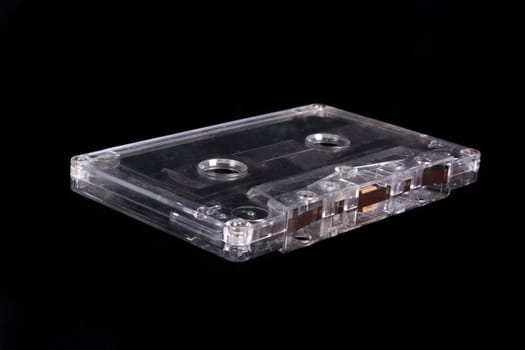 An old audio tape cassette, isolated on a black studio background.