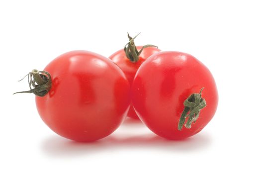 Cherry tomatoes with green tails, lie group. Their three. On a white background.