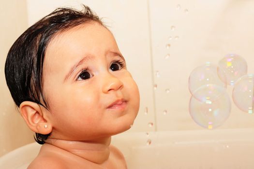 Adorable one-year old baby playing with foam in the bathroom