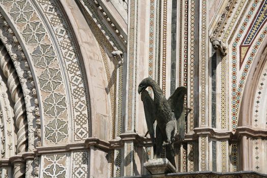 Detail of the facade of Orvieto Cathedral. (1290 - 1600 a. c.) Richly decorated with lots of stone mosaics and reliefs as well as pattern and artistic coils all over the facade. The eagel is a picture of the St John.