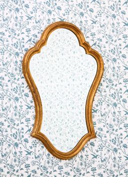 Golden Mirror Frame on Wall with Victorian Wallpaper.