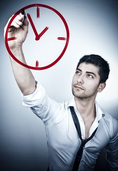 Young business man drawing a clock on a glass board