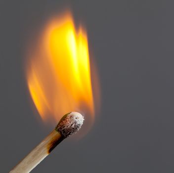 Green coated match head starts to burn with light blue smoke