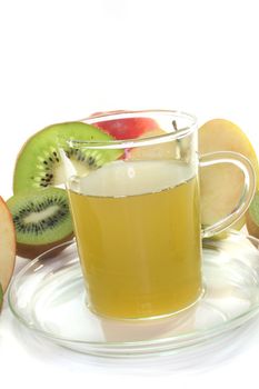 a glass of kiwi-apple tea with fresh kiwis and apples