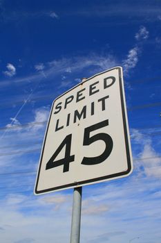 Speed limit road sign over blue sky.
