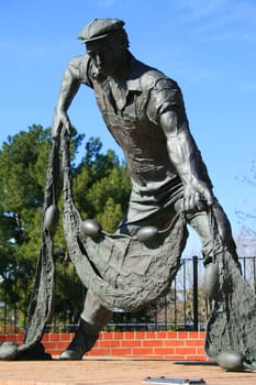 Statue of a working man in a park.

